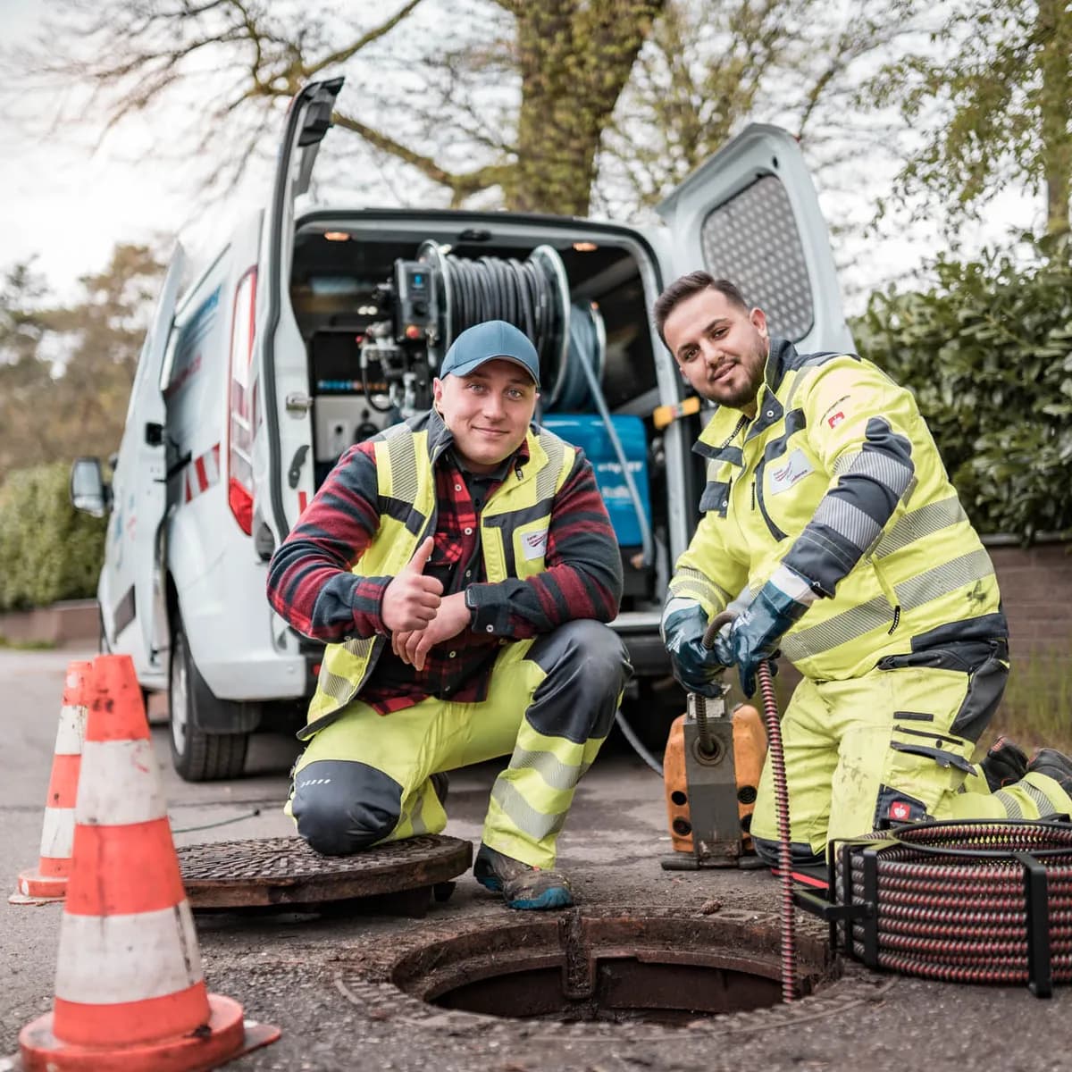 Techniker reinigt Kanal per Hochdruckspülung am Haus