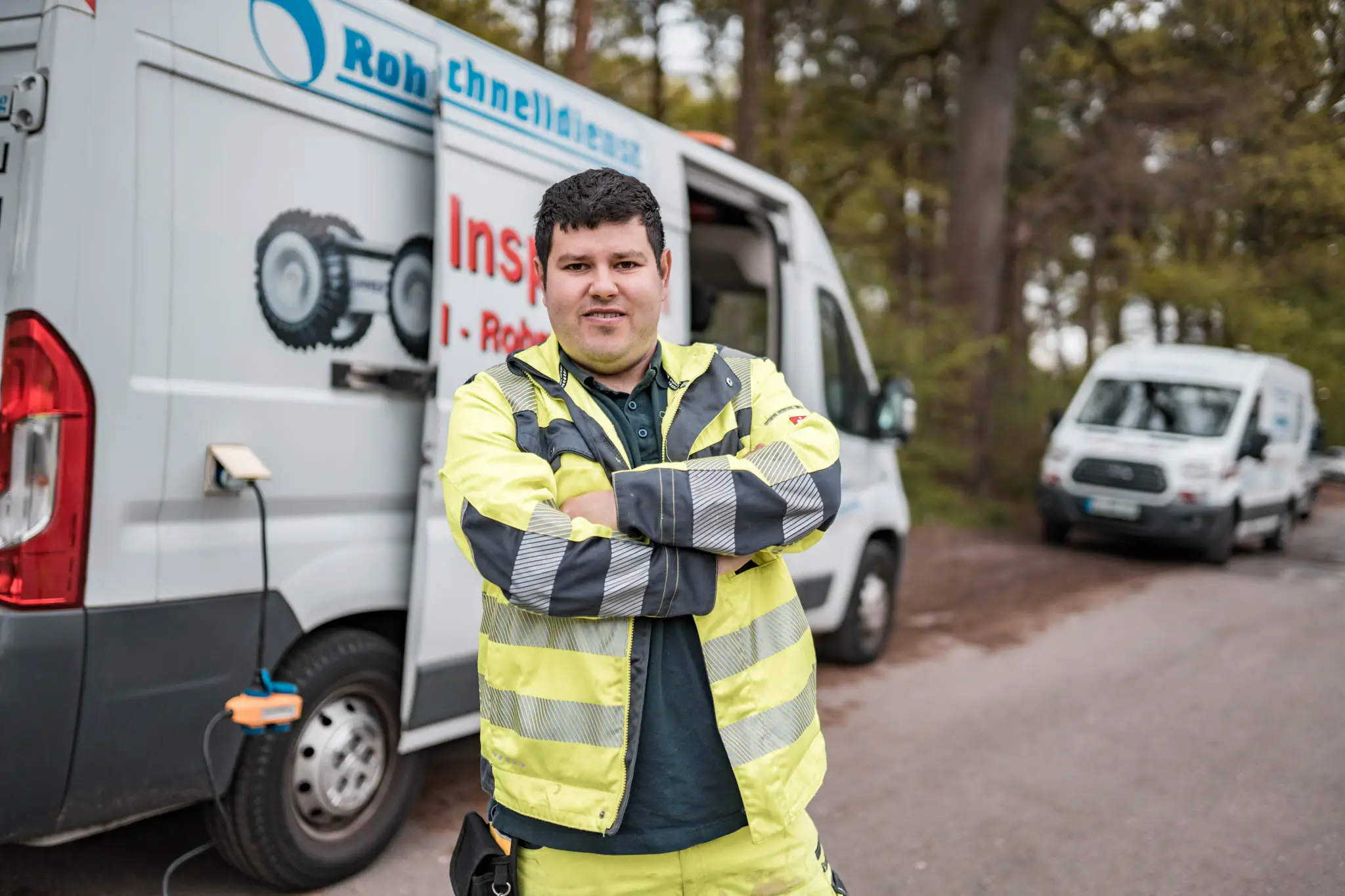 Fachmann für Rohrreinigung Benrath vor Firmenwagen auf Einsatz.